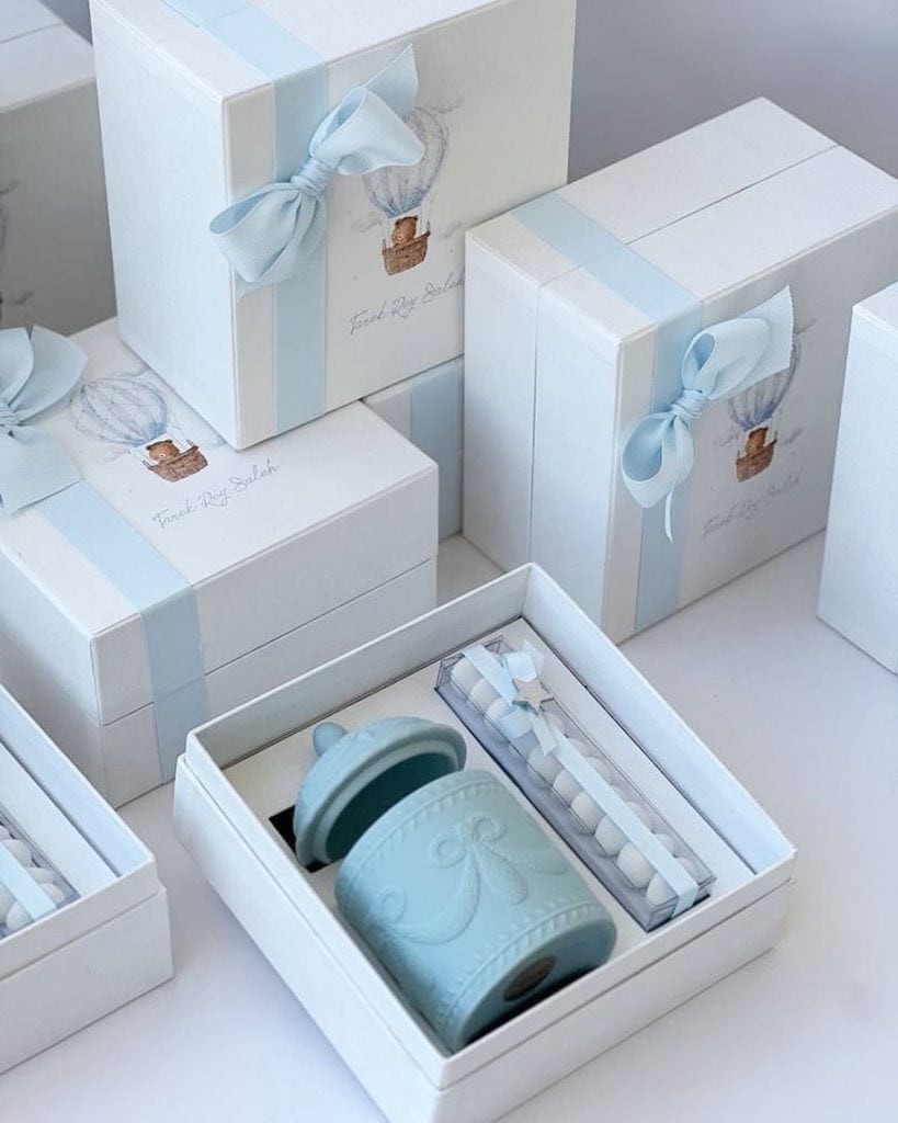 Delicate pastel blue baby shower or christening gift boxes with ribbons and custom tokens for newborn celebration.