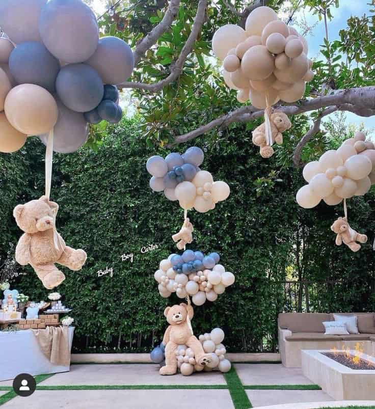 Colorful balloon decorations for a baby shower party with teddy bears and cozy seating.
