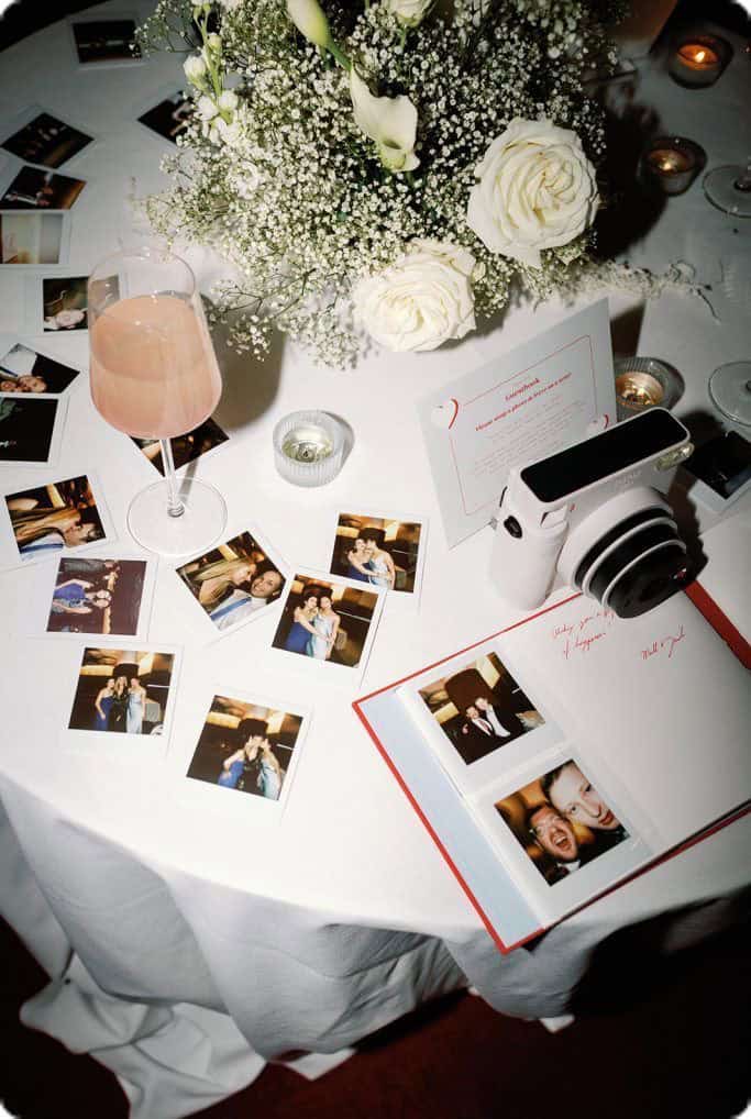 Photos of wedding reception table with flowers, Polaroid photos, and guestbook.