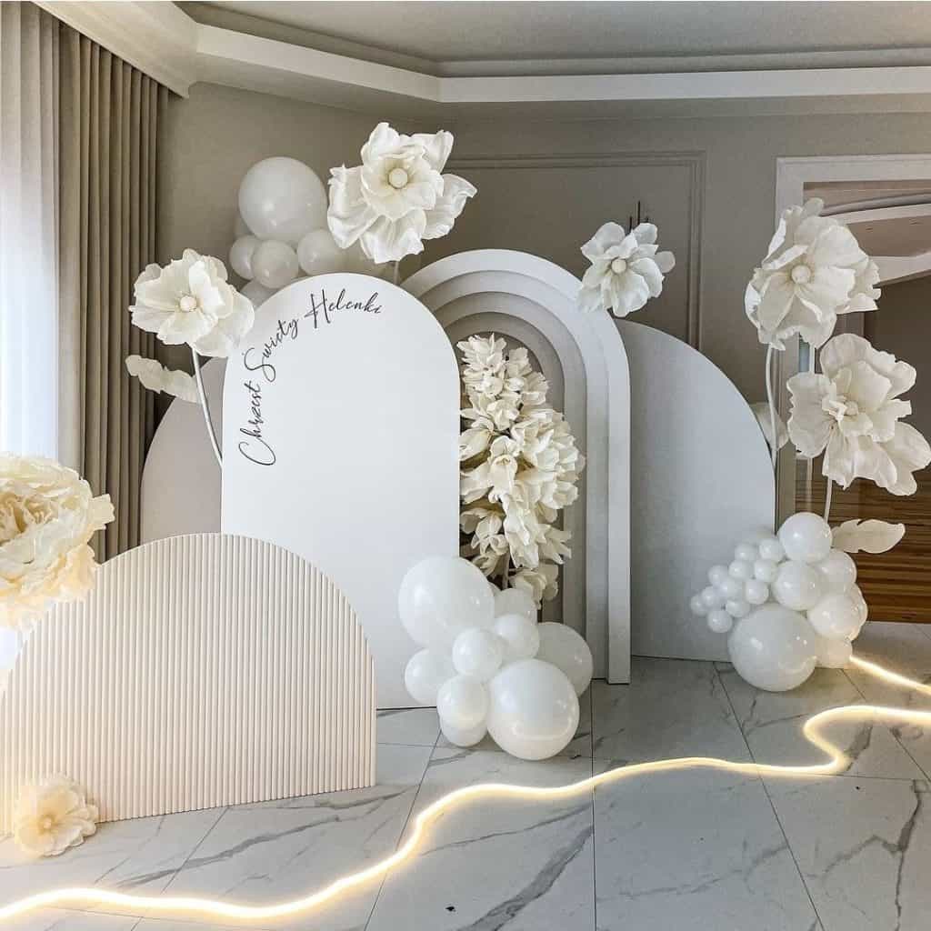 Elegant wedding event decoration with white flowers, balloons, and modern backdrops for chic celebrations.