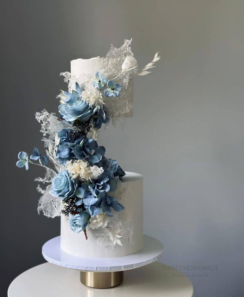 Elegant white cake with blue and white floral decoration, perfect for weddings and special events.