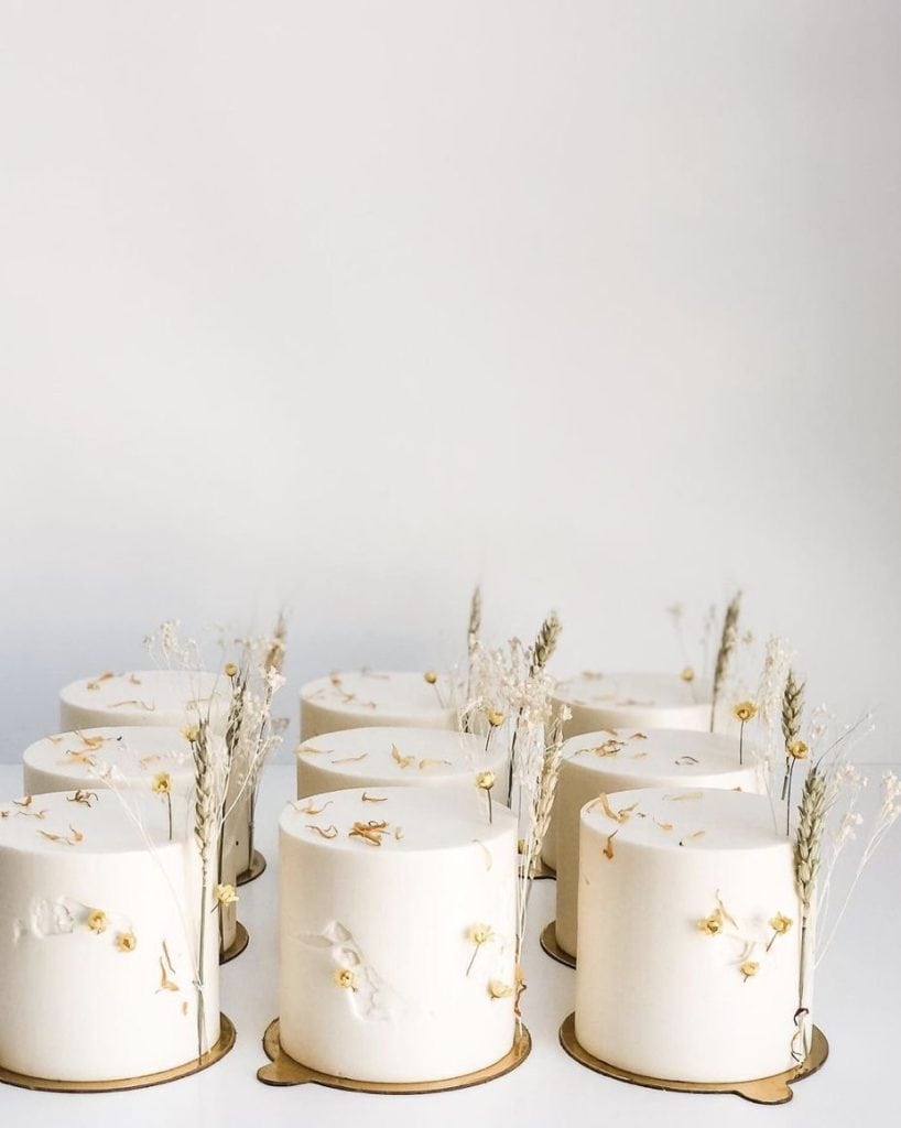 Elegant white event cakes decorated with dried flowers and minimalistic accents from UpEventi platform.