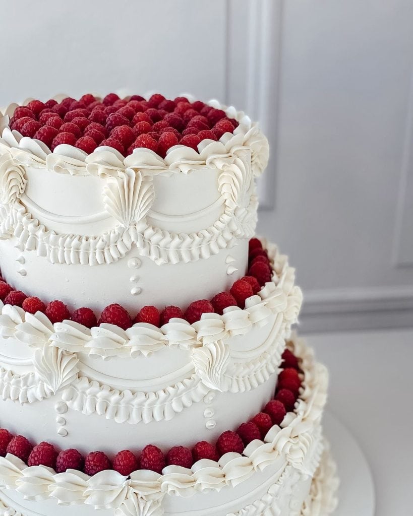 Delicious white wedding cake with raspberry decoration, perfect for events and celebrations.