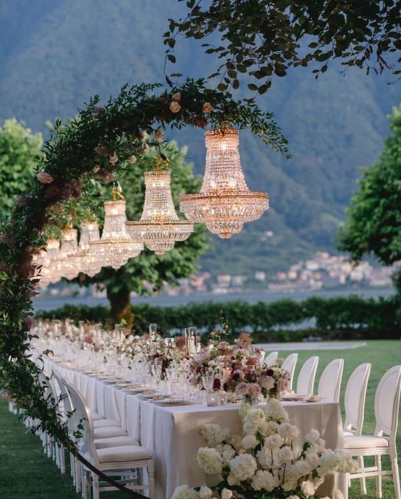 Elegant outdoor wedding reception with chandeliers, floral decor, and scenic mountain views.