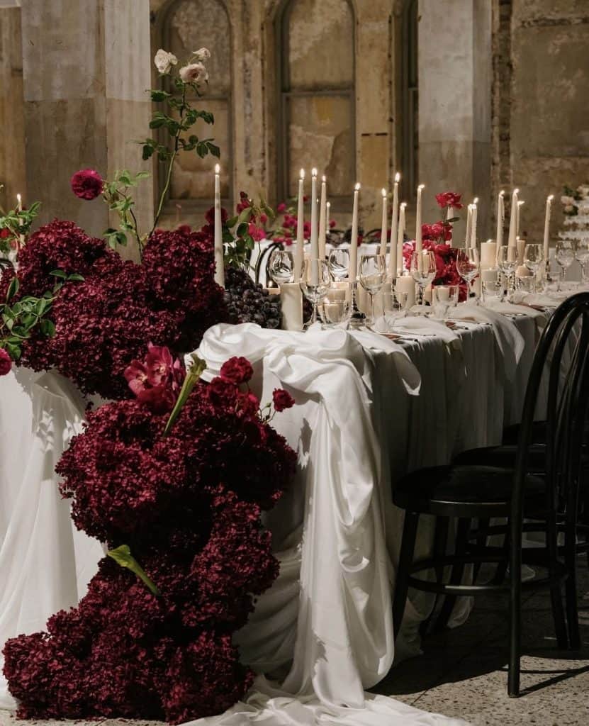 Elegant wedding table with red flowers and candles for upscale event.