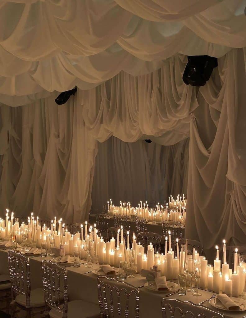 Elegant event decor with draped fabric and numerous candles for sophisticated gatherings at UpEventi.