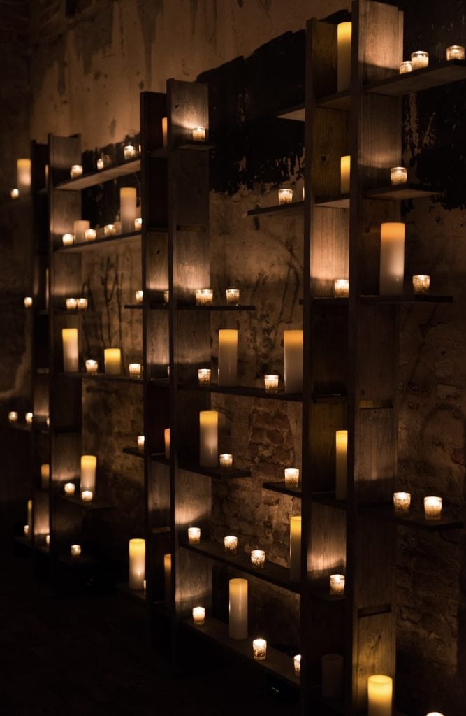 Candle-lit wall decor with wooden shelves, cozy ambiance for events or intimate gatherings.
