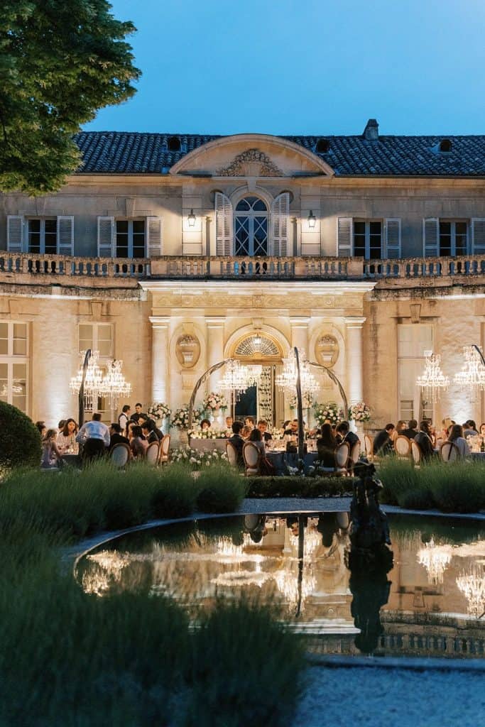 Elegant historic mansion hosting outdoor wedding reception at dusk with chandeliers and floral decor.