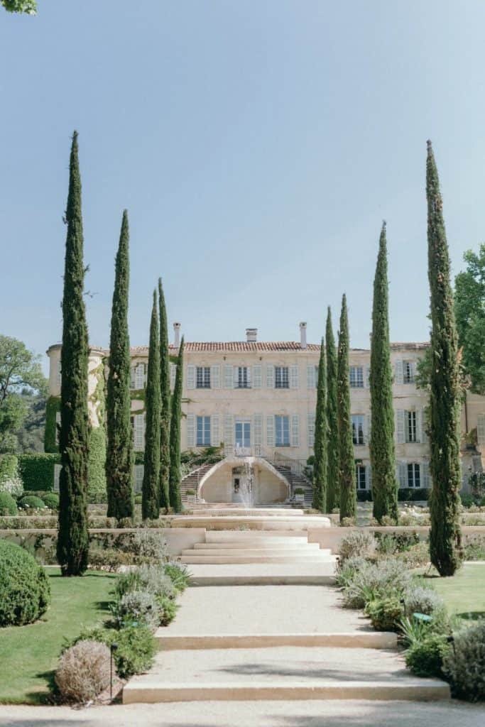 Luxurious mansion with tall cypress trees and manicured garden, perfect for event hosting.