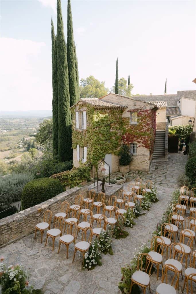 Charming outdoor wedding setup with elegant chairs and rustic stone pathway in scenic Italian countryside.