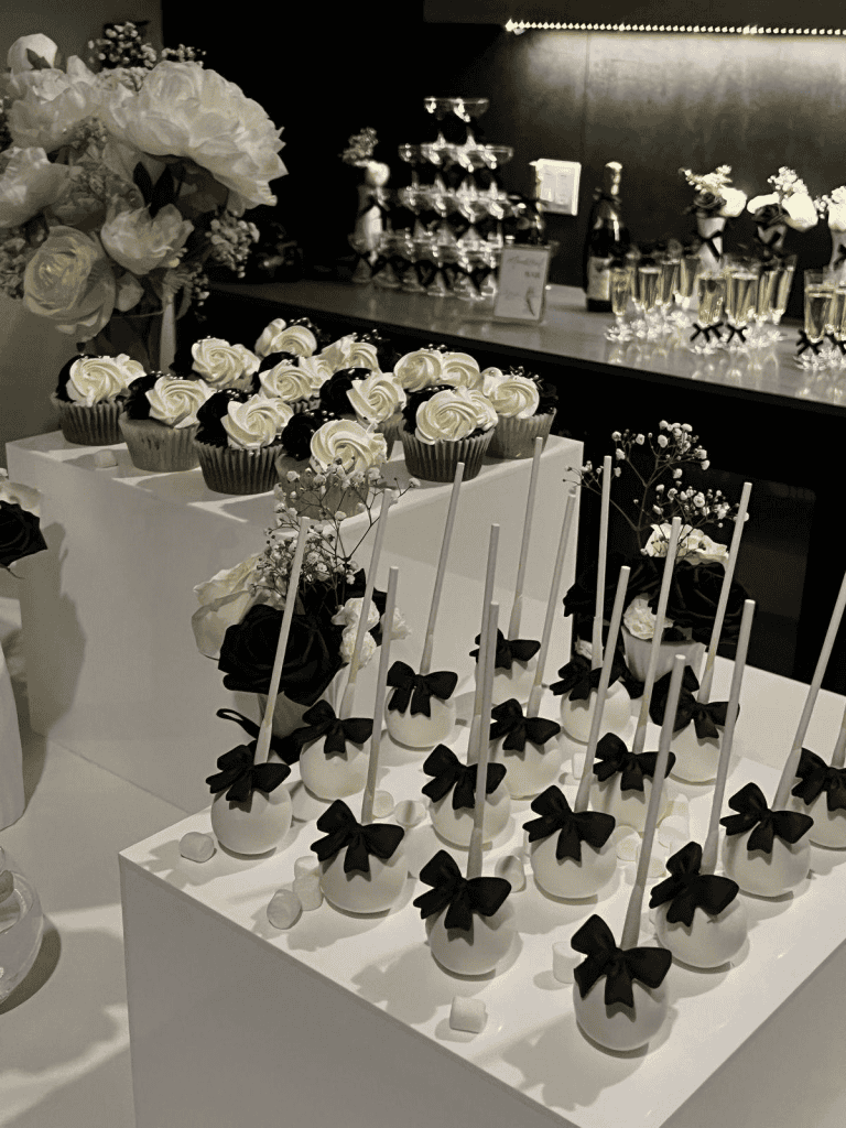 Elegant black and white dessert table with cupcakes and cake pops for an upscale event.